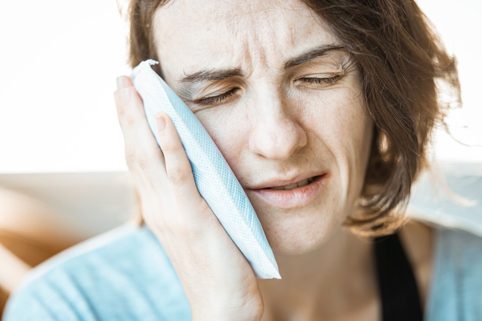 Woman holding a cloth-wrapped cold compress, the same barrier needed when using an ice pack on piles