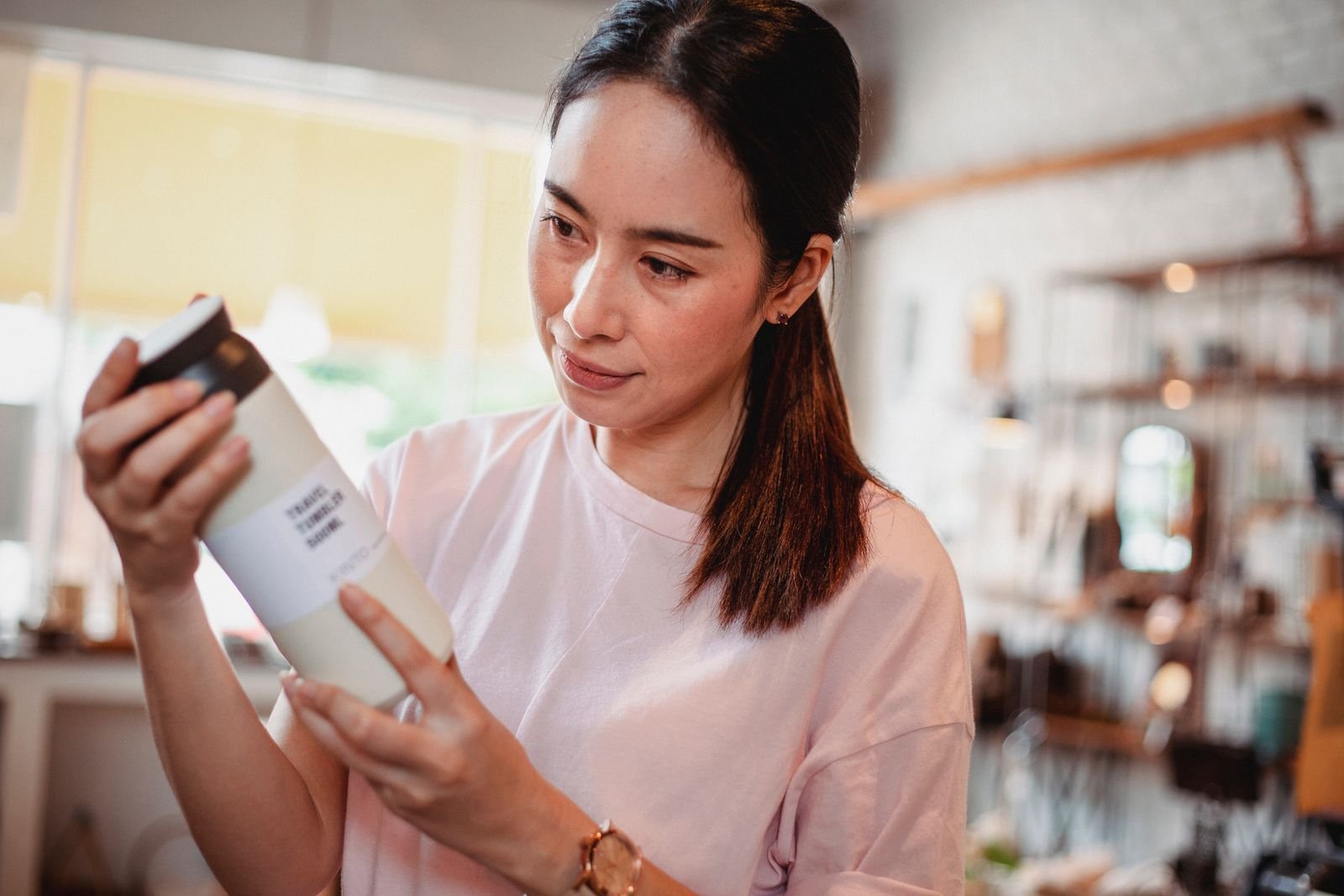 Woman reading a product label in a store, comparing strength and alcohol content in witch hazel wipes