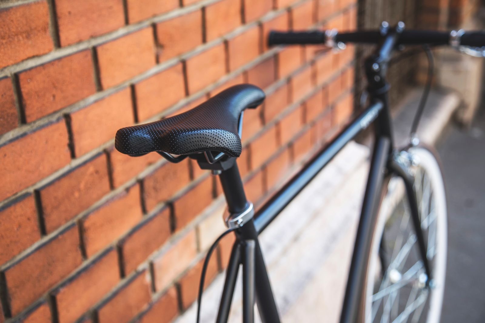 Bicycle saddle on a bike leaning against a brick wall, the main pressure point for anyone cycling with piles