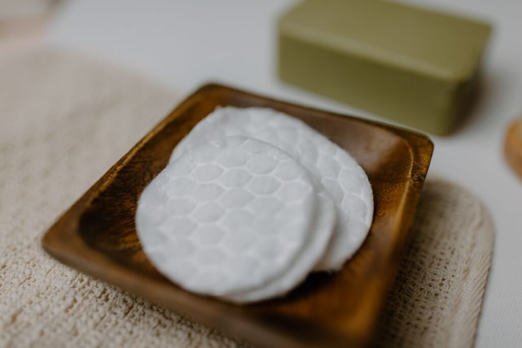 Round white cotton pads on a wooden tray, similar in shape to Tucks pads soaked in witch hazel