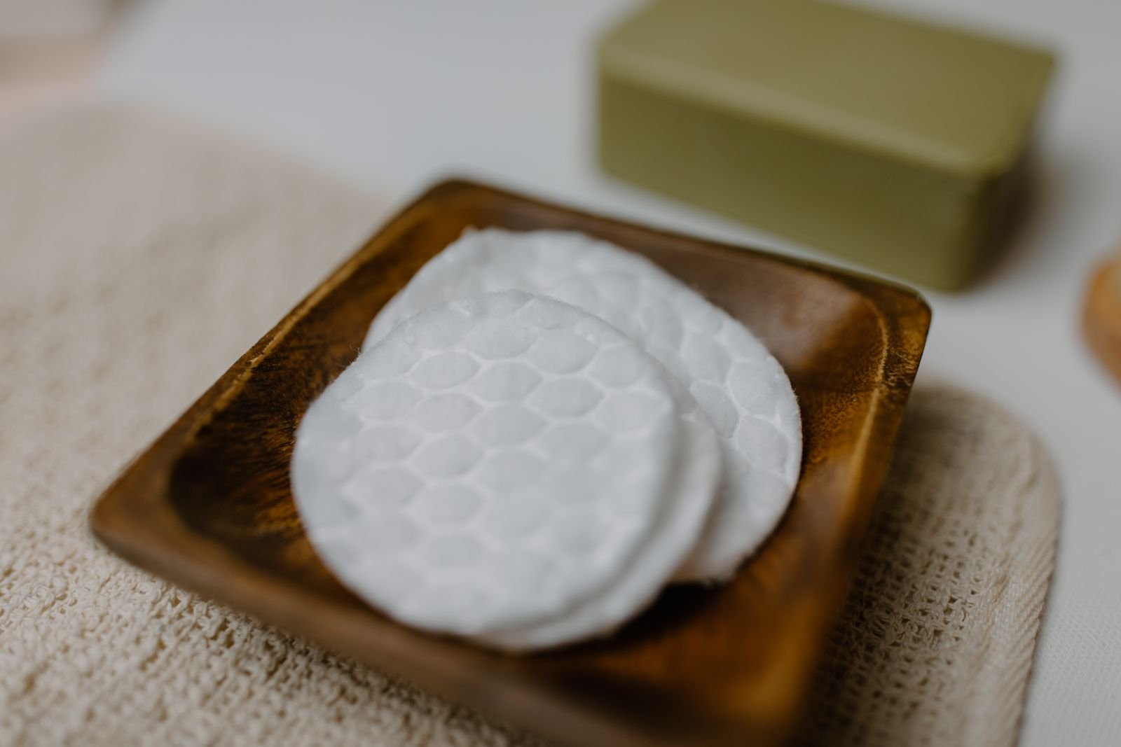Round white cotton pads on a wooden tray, similar in shape to Tucks pads soaked in witch hazel