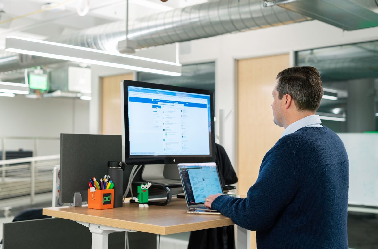 Man working at a standing desk, taking pressure off while waiting to see how long external hemorrhoids last