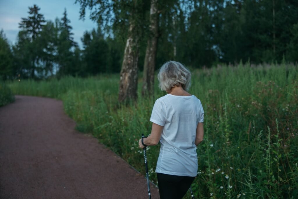 Older woman walking on a park trail with poles, the kind of steady activity that may help hemorrhoids