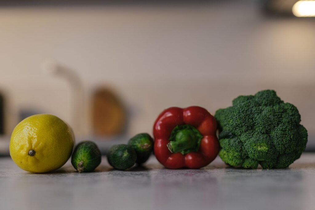 Lemon, cucumbers, red pepper, and broccoli on a counter, fiber foods that help hemorrhoids go away on their own