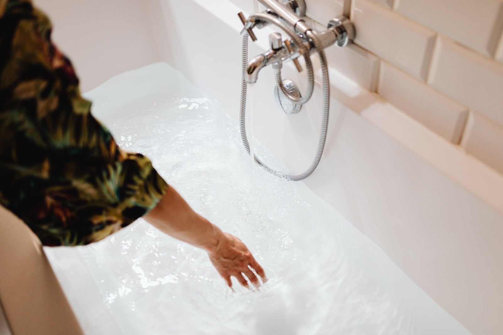 Hand testing warm bath water, a sitz bath that adds comfort while hemorrhoids go away on their own