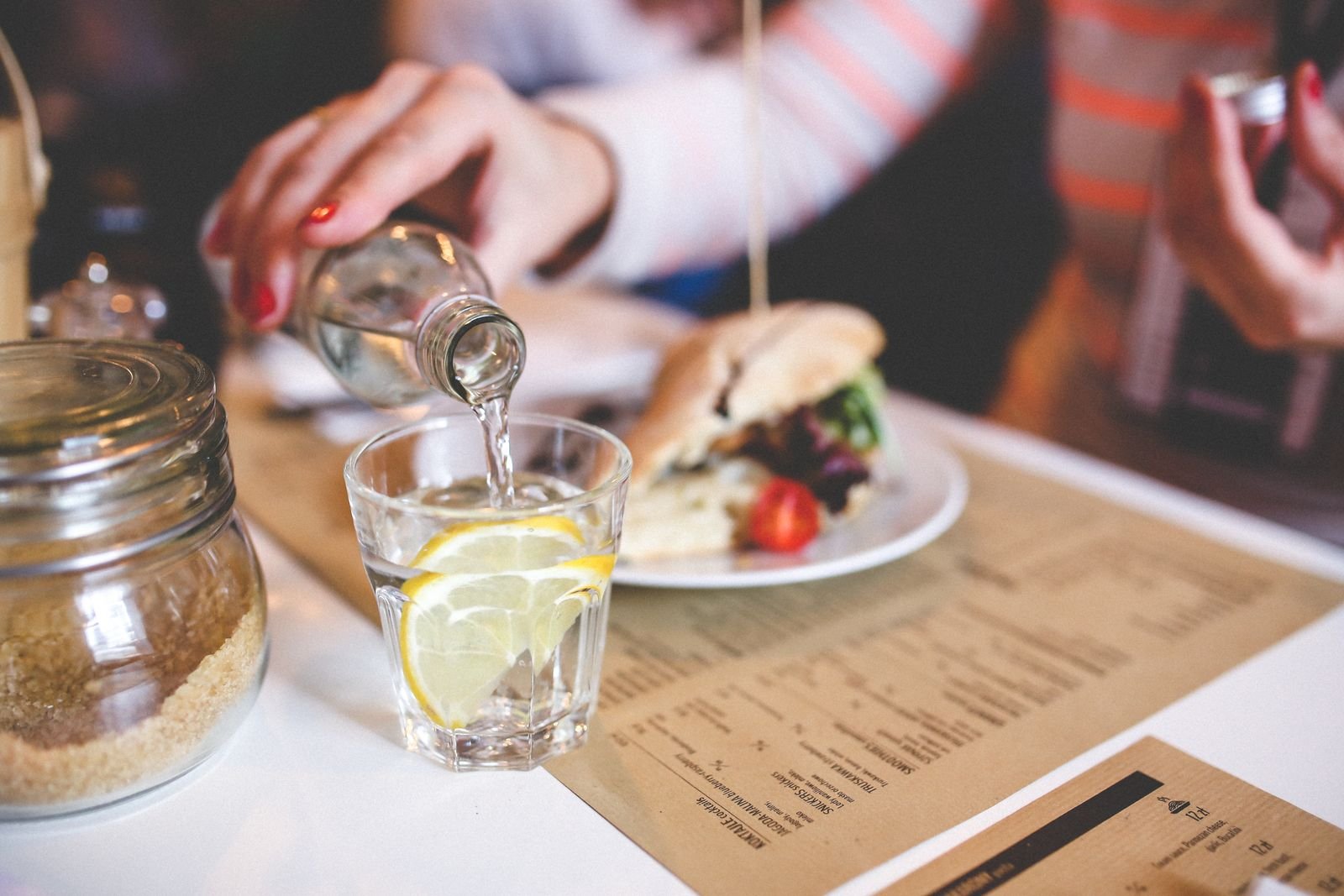 Water poured into a glass with lemon at a restaurant table, a simple way to keep alcohol from making hemorrhoids worse